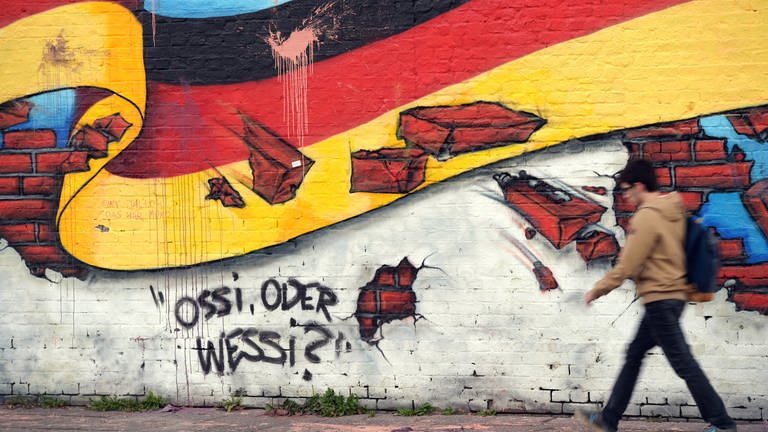 Wandbild in Berlin 2015 mit der deutschen Nationalflagge und dem Schriftzug "Ossi oder Wessi?" (Foto: picture-alliance / Reportdienste, (c) dpa)