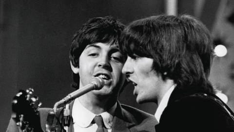 Die beiden Beatles Paul McCartney und George Harrison singen im August 1965 (Foto: imago images, imago/Cinema Publishers Collection)
