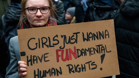 Frau hält Pappschild mit der Aufschrift: "Girls just wanna have FUNdamental Human Rights!": Solidaritäts-Kundgebung 2018 an der Warschauer Brücke in Berlin gegen die Verschärfung der Gesetze in Polen bei Schwangerschaftsabbrüchen  (Foto: imago images, IMAGO / snapshot)