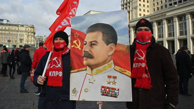 Am Todestag von Stalin, der am 5. März 1953 starb, nehmen im März 2022 Mitglieder der Kommunistischen Partei Russlands an einer Blumenniederlegungszeremonie am Grab des sowjetischen Führers Joseph Stalin an der Kremlmauer teil. Vor sich tragen sie ein Porträt Stalins. (Foto: IMAGO, IMAGO / SNA)