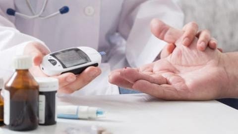Eine Ärztin misst mit einem Gerät den Zuckerspiegel eines Patienten dem ein Blutstropfen aus dem Finger quillt (Foto: Getty Images, Thinkstock -)