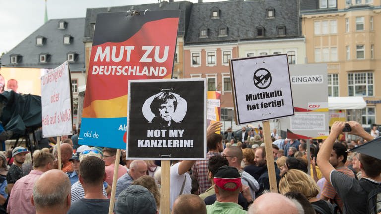 Demonstranten während eines Wahlkampfauftritts von Angela Merkel (Foto: picture-alliance / Reportdienste, picture alliance/Sebastian Kahnert/dpa-Zentralbild/dpa)
