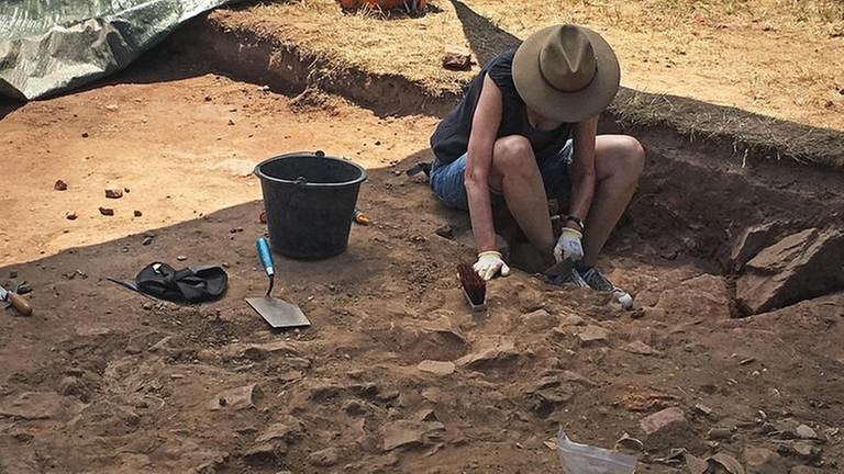Eine Frau sitzt an einer römischen Ausgrabungsstätte und legt Funde frei (Foto: SWR, SWR - Frank Scheuer)