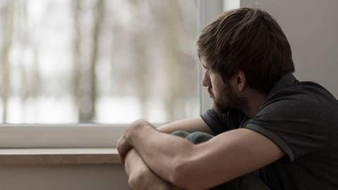 Ein Mann schaut deprimiert aus dem Fenster (Foto: Getty Images, Thinkstock -)