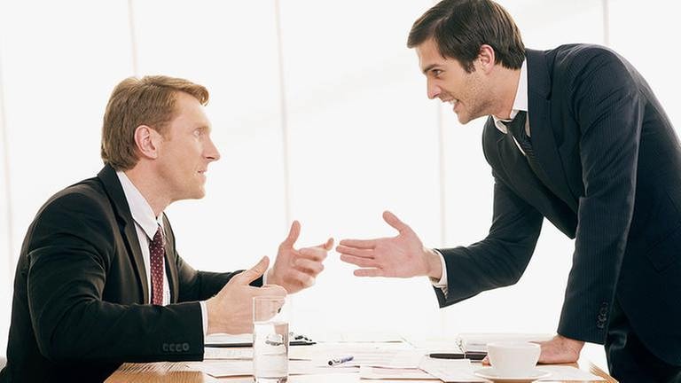 Zwei Männer in Anzügen streiten lautstark und gestikulierend in einem Büro. (Foto: Getty Images, Thinkstock -)
