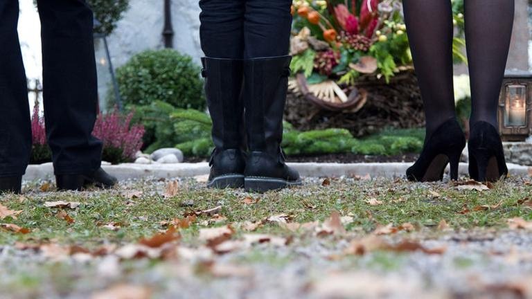 Drei Personen stehen vor einem Grab (Foto: Getty Images, Thinkstock -)