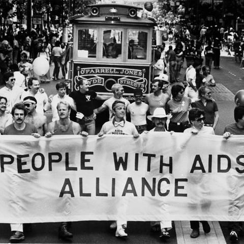 Demonstranten tragen während der 13. jährlichen Gay Freedom Day Parade am 27. Juni 1983 in San Francisco ein Banner mit der Aufschrift "People With Aids Alliance" (Foto: picture-alliance / Reportdienste, picture alliance / AP Images)
