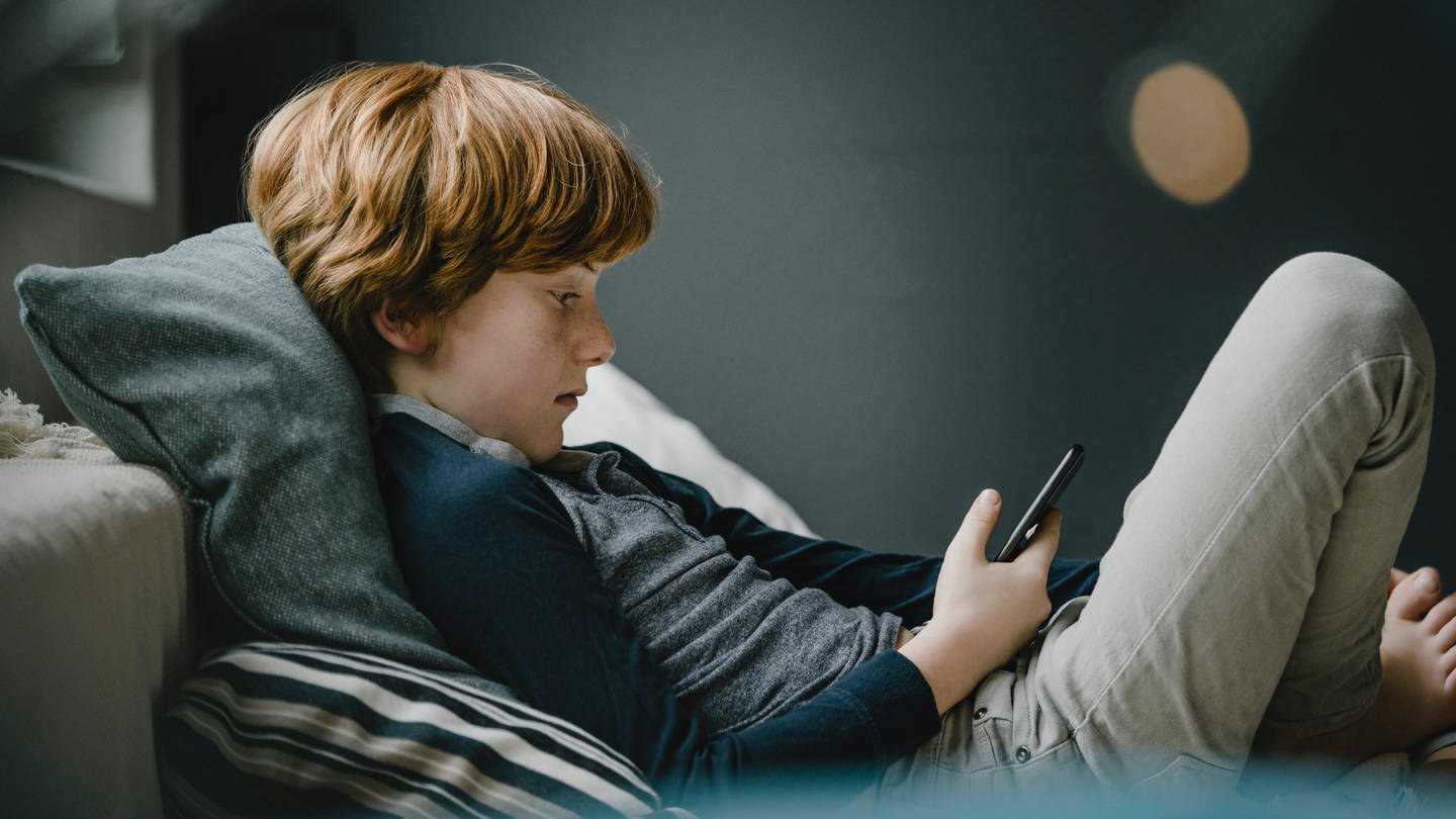 Ein Junge liest auf einem Smartphone (Foto: IMAGO, imago images/Westend61)
