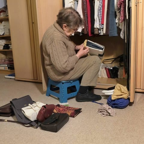 Eine Seniorin räumt den Schrank auf. Döstädning ist ein Aufräum-Trend aus Schweden: vor dem Tod aussortieren und entrümpeln, um den Angehörigen geordnete Verhältnisse zu hinterlassen. (Foto: IMAGO, IMAGO / Martin Wagner)
