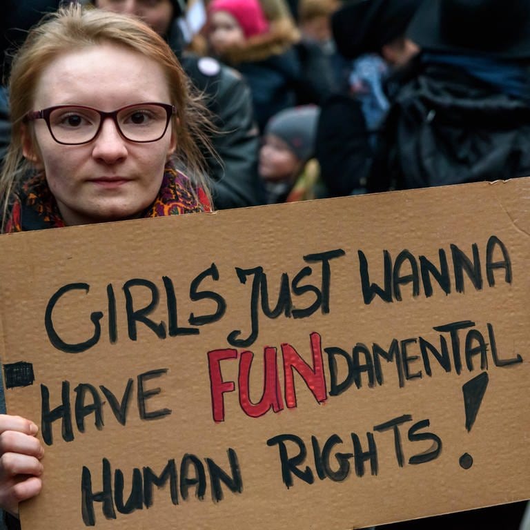 Frau hält Pappschild mit der Aufschrift: "Girls just wanna have FUNdamental Human Rights!": Solidaritäts-Kundgebung 2018 an der Warschauer Brücke in Berlin gegen die Verschärfung der Gesetze in Polen bei Schwangerschaftsabbrüchen  (Foto: IMAGO, IMAGO / snapshot)