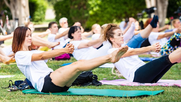 Eine Gruppe von Menschen praktiziert Yoga auf einer Wiese: Für Krebspatienten ist es sehr wichtig, sich zu Bewegen und Sport zu treiben. Auch sanfte Sportarten wie Yoga oder Qigong sind geeignet. (Foto: picture-alliance / Reportdienste, picture alliance / PIXSELL | Milan Sabic)