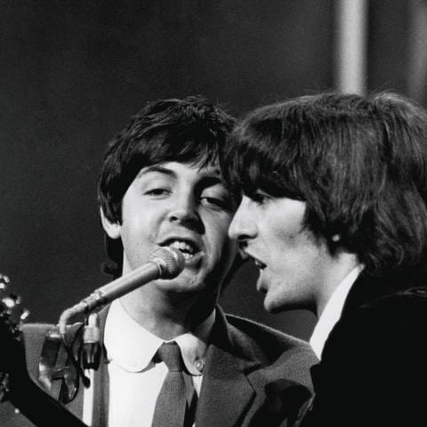 Die beiden Beatles Paul McCartney und George Harrison singen im August 1965 (Foto: IMAGO, imago/Cinema Publishers Collection)
