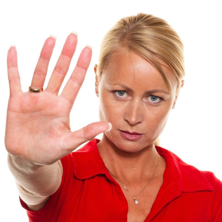 Frau signalisiert "Stop" mit der ausgestreckten Hand: Wer meldet sich im Internet gegen Hassrede zu Wort? Wer mischt sich ein, wenn jemand im Bus bedroht oder am Arbeitsplatz diskriminiert wird? Menschen, die couragiert dagegenhalten, widerstehen dem Druck, sich einer Mehrheit anzupassen. Sie zeigen sozialen Mut und Handlungskompetenz.  (Foto: IMAGO, IMAGO / blickwinkel)