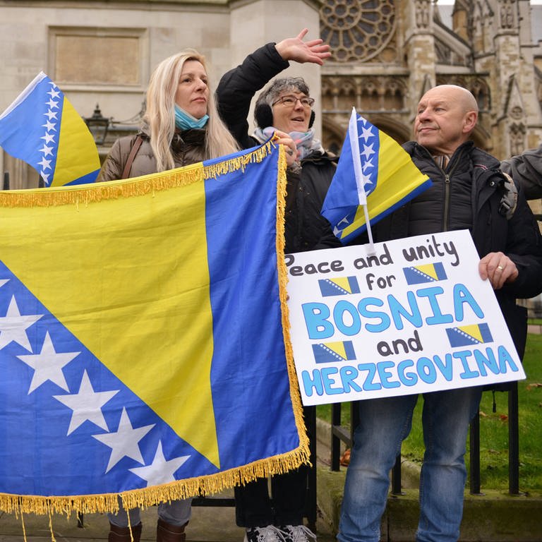 Demonstranten halten während einer Kundgebung Fahnen und Transparente hoch: Die bosnisch-herzegowinische Diaspora und Unterstützer der Einheit des Landes versammelten sich am Parliament Square in London, um das Bewusstsein für eine potenzielle neue Krise in Bosnien zu schärfen. (Foto: IMAGO, IMAGO / ZUMA Wire)