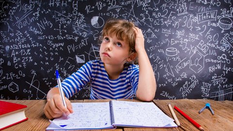 Junge sitzt vor Schultafel mit vielen Matheaufgaben und denkt nach: Schlecht in Mathe – oft liegt das an schlechtem Unterricht, nicht an mangelndem Talent. Gute Mathe-Didaktik setzt auf Verstehen statt auswendig lernen und begeistert für das Fach. (Foto: Colourbox)