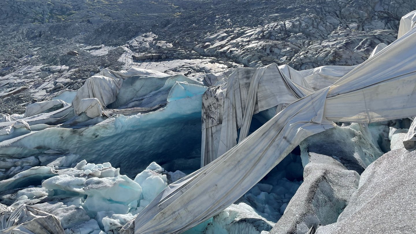 Wie schlaffe Gespenster hängen die Tücher über dem Eis, das tatsächlich deutlich höher ist als auf der Gletscherzunge dahinter (August 2022) (Foto: SWR, Kathrin Hondl / ARD Studio Genf)