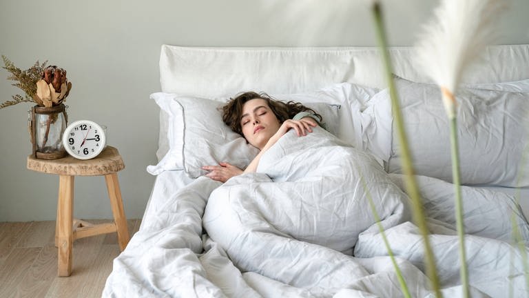 Eine junge Frau liegt im Bett und schläft friedlich (Foto: IMAGO, IMAGO / Westend61)