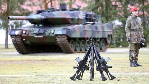 Ein Panzersoldat steht im Februar 2020 in der von-Hardenberg-Kaserne vor einem Leopard 2 Panzer und aufgestellten Gewehren vom Typ G36 von Heckler & Koch (Foto: picture-alliance / Reportdienste, picture alliance/dpa | Wolfgang Kumm)