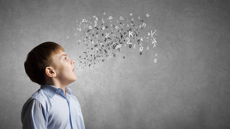 Junge mit geöffnetem Mund, dem viele Buchstaben "entfliegen": Stottern beginnt im Gehirn und es gibt erbliche Faktoren. (Foto: IMAGO, IMAGO / Shotshop)