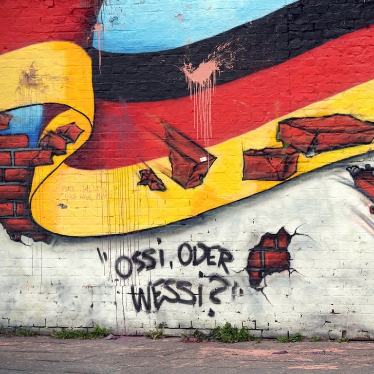 Wandbild in Berlin 2015 mit der deutschen Nationalflagge und dem Schriftzug "Ossi oder Wessi?" (Foto: picture-alliance / Reportdienste, (c) dpa)