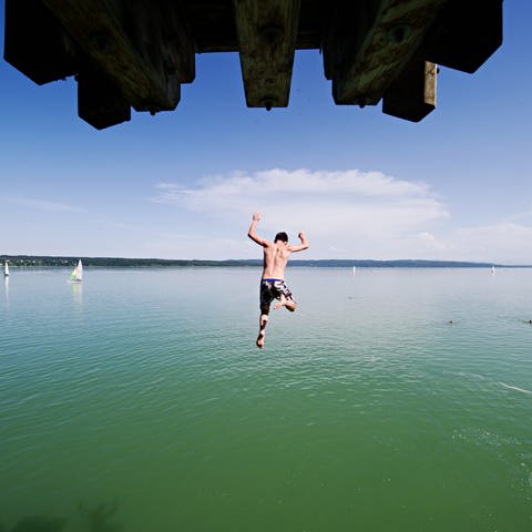 Ein Mann springt von einem Sprungturm ins kühle Wasser (Foto: picture-alliance / Reportdienste, picture alliance / dpa | Nicolas Armer)