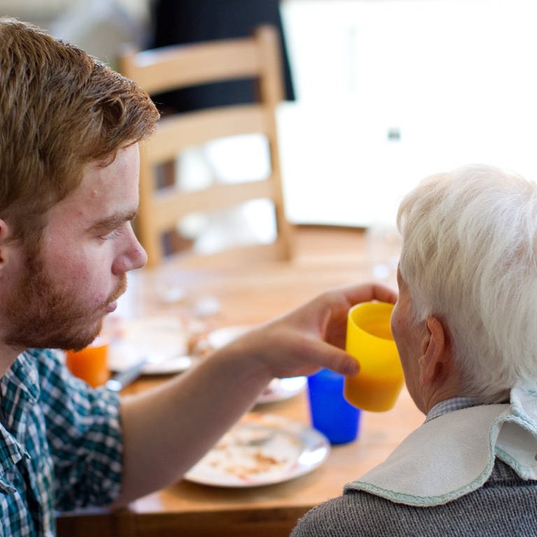 Junger Mann hilft einer älteren Frau beim Einnehmen einer Mahlzeit. (Foto: picture-alliance / Reportdienste, picture alliance / dpa | Friso Gentsch)