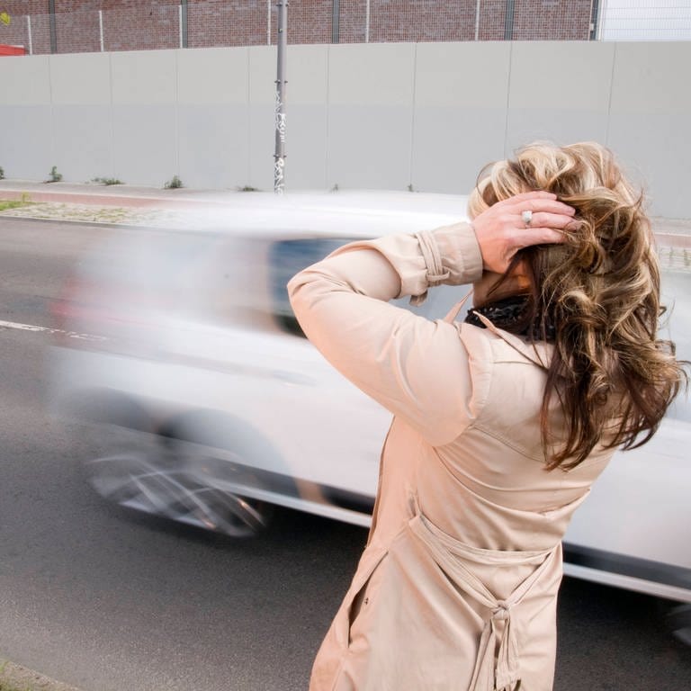 Eine Frau steht an einer Straße und hält sich die Ohren zu (Foto: IMAGO, IMAGO / Shotshop)