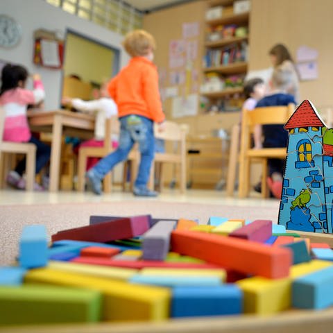 Spielzeug liegt in einer Kindertagesstätte auf dem Boden, im Hintergrund Kinder. (Foto: picture-alliance / Reportdienste, picture alliance / Monika Skolimowska/dpa | Monika Skolimowska)