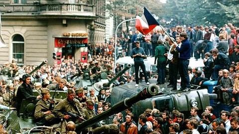 Demonstranten protestieren und umringen in der Prager Innenstadt sowjetische Panzer. Einige stehen mit einer Fahne der Tschechoslowakei auf einem umgekippten Militärfahrzeug (Foto: picture-alliance / dpa, picture-alliance / dpa - Libor Hajsky)