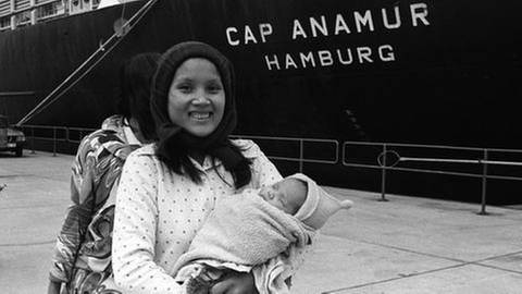 Eine junge Frau mit Kind steht vor demm Rettungsschiff "Cap Anamur" (Foto: picture-alliance / dpa, picture-alliance / dpa -)