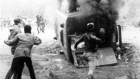 Rund 200 zum Teil vermummte Demonstranten griffen am 20. Mai 1986 in Wackersdorf an einer Zufahrtstraße eine Polizeikontrolle an, warfen diesen Mannschaftswagen um und setzten ihn in Brand.  (Foto: dpa Bildfunk, picture-alliance/ dpa | DB dpa)