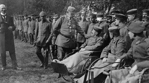 Paul von Hindenburg besucht Verwundete des Ersten Weltkrieges, Soldaten in Reihe aufgestellt, im Vordergrund in Rollstühlen (Foto: SZ Photo - Scherl)