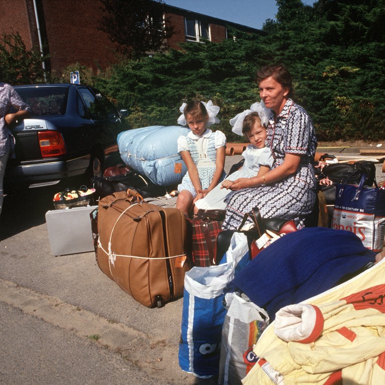 Aussiedler aus Kasachstan sitzen am 21. August 1989 im Lager Schöppingen auf ihren gepackten Koffern. Sie werden verlegt, um Platz für Flüchtlinge aus der DDR zu machen.  (Foto: picture-alliance / Reportdienste, Franz-Peter Tschauner)