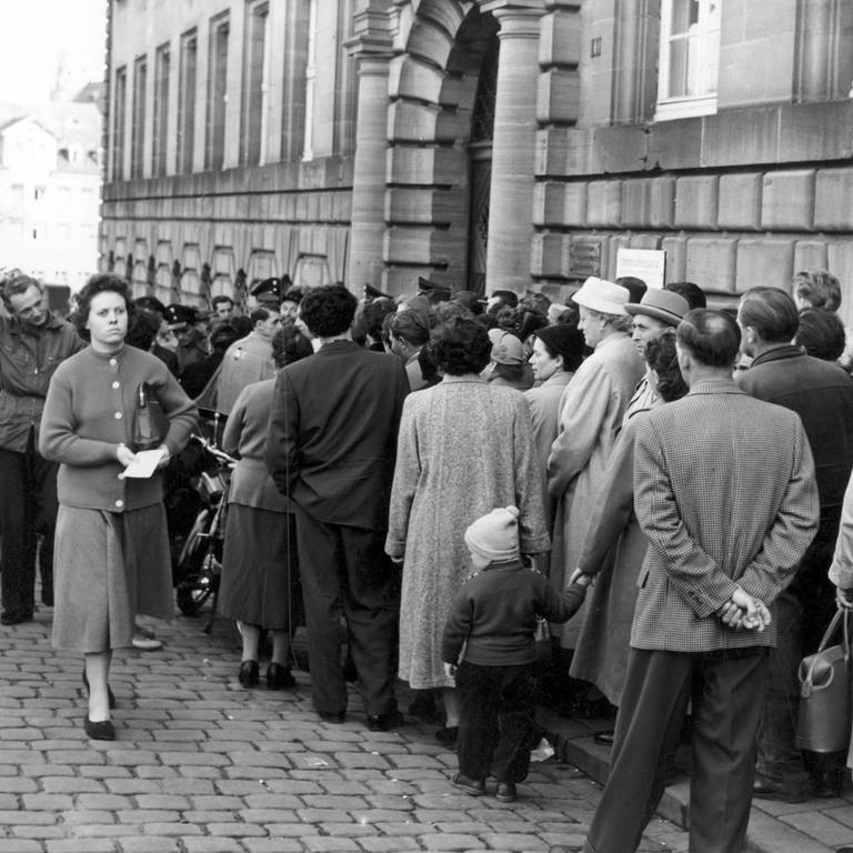 Menschen stehen am 18.10.1957 vor der Ortskrankenkasse in Nürnberg Schlange. Der Andrang war so groß, dass die Nürnberger Stadtpolizei zur Hilfeleistung herangezogen wurde. (Foto: picture-alliance / Reportdienste, Karl Schnörrer/(c) dpa - Report)