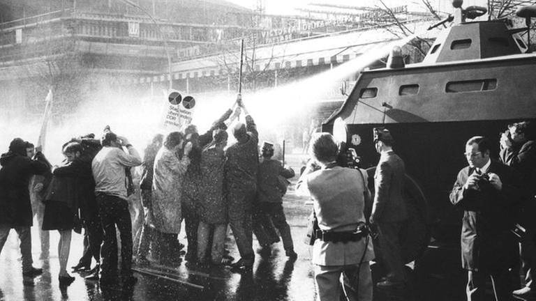 Demonstranten mit Kreuz vor einem Wasserwerfer am 14.4.1968, Ostersonntag, auf dem Kurfürstendamm in Berlin (Foto: picture-alliance / dpa, picture-alliance / dpa -)