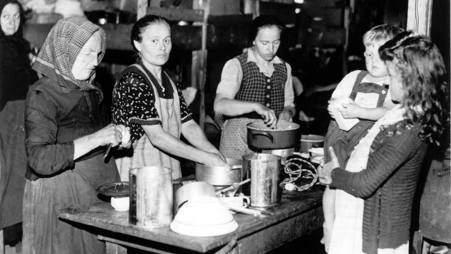 Frauen bereiten 1948 an einem Tisch im bayerischen Flüchtlingslager Allach Mahlzeiten zu (Foto: dpa Bildfunk, Picture Alliance)