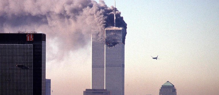 Ein entführtes Verkehrsflugzeug nähert sich dem World Trade Center. Am 11. September 2001 flog es in New York in den Wolkenkratzer, einem Wahrzeichen der Stadt. (Foto: picture-alliance / Reportdienste, picture-alliance / dpa | Seth_Mccallister)