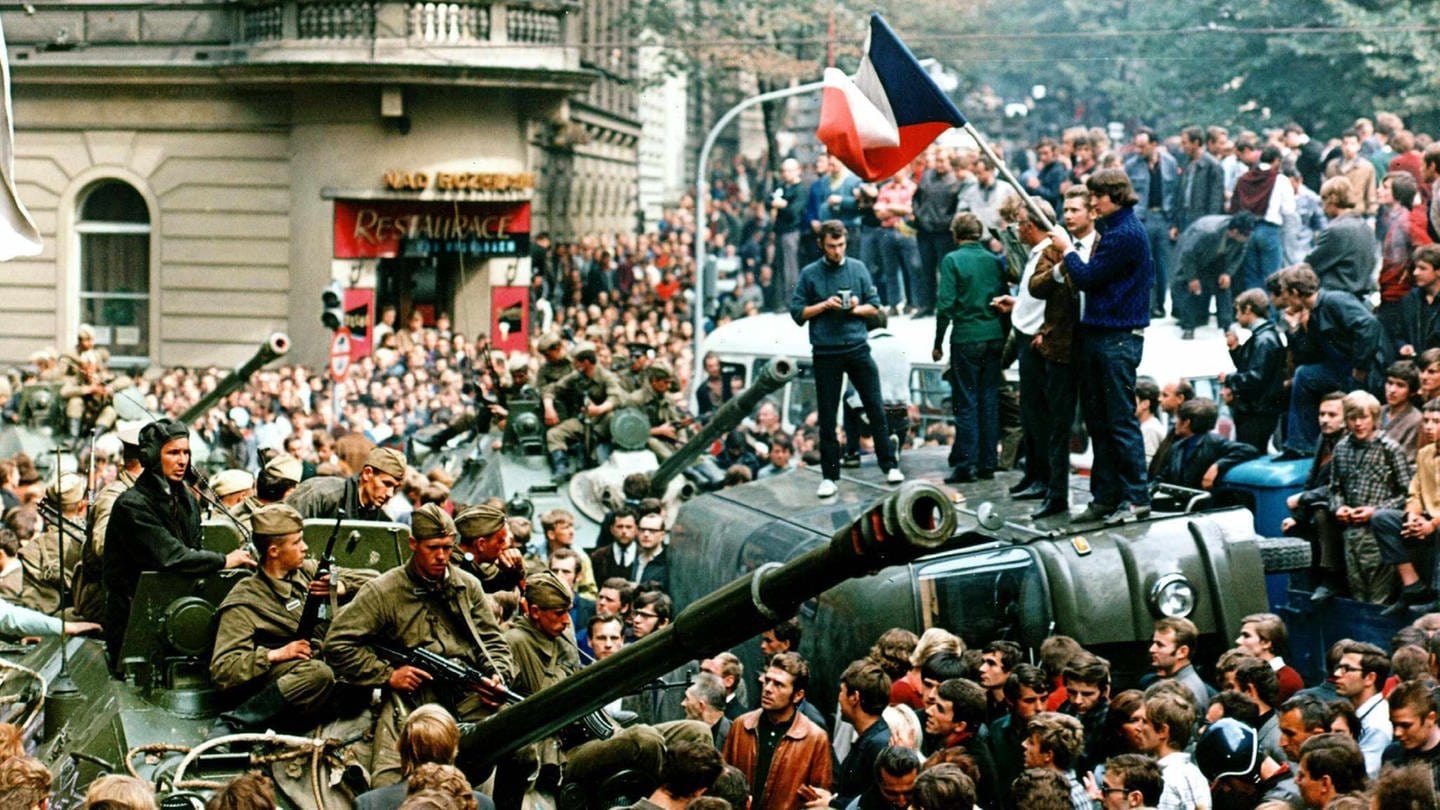 picture alliance/dpa | Libor Hajsky (Foto: picture-alliance / Reportdienste, Demonstranten protestieren und umringen in der Prager Innenstadt sowjetische Panzer. Einige stehen mit einer Fahne der Tschechoslowakei auf einem umgekippten Militärfahrzeug.)