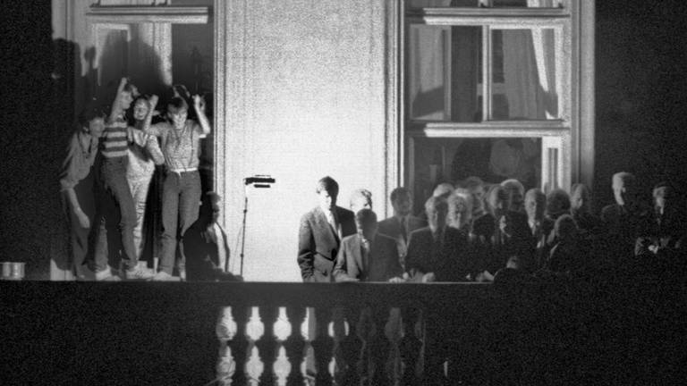 Der damalige Außenminister Hans-Dietrich Genscher (unter dem Fensterkreuz rechts) mit anderen Politikern auf dem Balkon der bundesdeutschen Botschaft in Prag. Am 30. September 1989 hatte der FDP-Politiker dort den DDR-Bürgern im Garten verkündet, dass ihre Ausreise möglich geworden war. (Foto: dpa Bildfunk, picture alliance / dpa | Reinhard Kemmether)