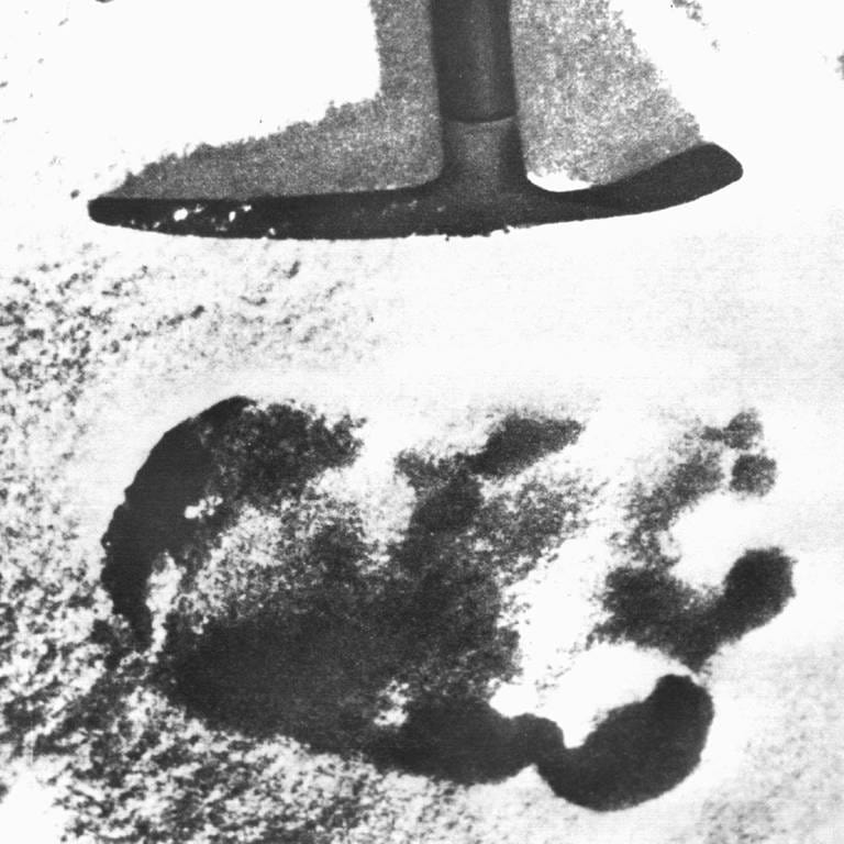 Das Archivbild von 1951 zeigt eine Spitzhacke, die auf einen großen unidentifizierten Fußabdruck im Schnee des Himalaya deutet. Eine Expedition stieß 1951 auf den Abdruck und schrieb ihn dem sagenumworbenen Schneemenschen Yeti zu. (Foto: picture-alliance / Reportdienste, dpa Bildfunk, picture alliance / dpa )