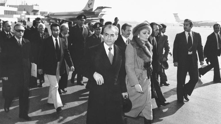 Schah Mohammad Reza Pahlavi und Kaiserin Farah gehen am 16.1.1979 über das Rollfeld des Mehrabad Airport zu einem Flugzeug, um das Land zu verlassen. Der Schah verließ im Zuge der islamischen Revolution von seinen Thron. (Foto: dpa Bildfunk, picture alliance/dpa | Uncredited)