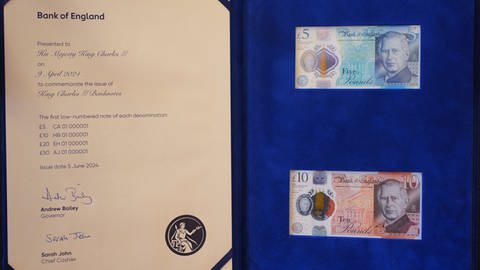 König Charles Banknoten: Auf dem Foto sind zwei eingerahmte Geldscheine zu sehen mit einem Portrait des britisches Königs. In diesem Fall 5 und 10 Pfund.