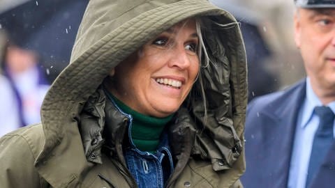 Königin Máxima der Niederlande mit einer Kapuze im Regen