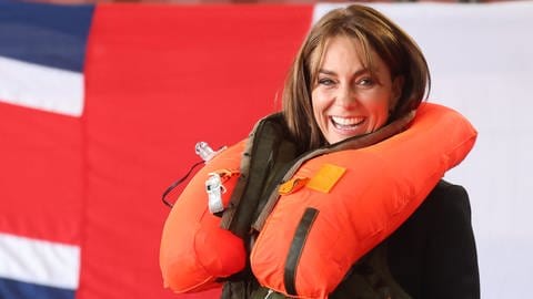 Prinzessin Kate lacht natürlich, nachdem sie bei einem Besuch der Royal Navy eine orangene Rettungsweste betätigt hat und diese sich geöffnet hat und schließlich voller Luft um ihren Hals liegt. (Foto: dpa Bildfunk, Picture Alliance)