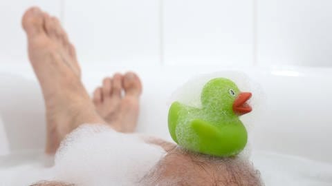 Komiker Loriot und seine Sprüche und Sketche: Eine grüne Badeente sitzt auf dem Knie eines Mannes, der ein Vollbad mit viel Schaum nimmt. (Foto: IMAGO, Panthermedia)