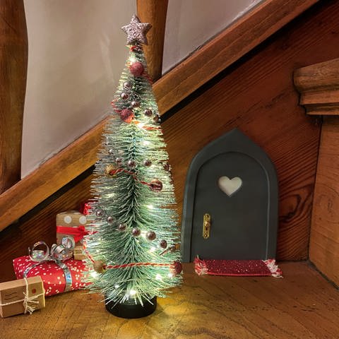Trend für Weihnachten 2023: An einer Holztreppe ist im Advent eine kleine Wichteltür befestigt. Davor steht ein kleiner, geschmückter Deko-Weihnachtsbaum. (Foto: SWR)