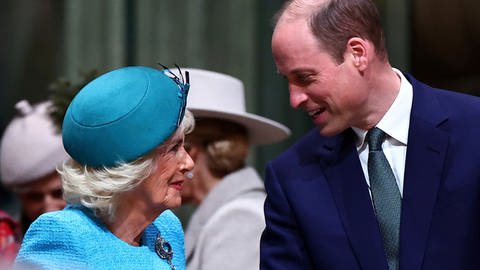 Königin Camilla und Prinz William blicken sich an reden miteinander beim Commonwealth Day in der Westminster Abbey. Sie trägt ein hellblaues Kostüm mit passendem Hut. Prinz WIlliam einen dunkelblauen Anzug. (Foto: dpa Bildfunk, picture alliance/dpa/Pool AFP | Henry Nicholls)