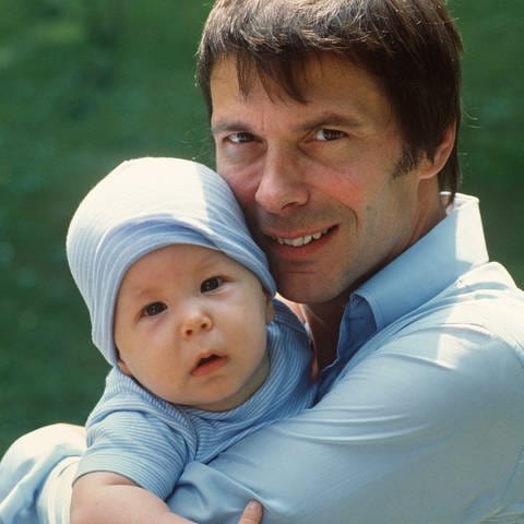 Der deutsche Sänger Reinhard Mey ("Über den Wolken") hält seinen kleinen Sohn Max auf dem Arm und lächelt in die Kamera (1982) (Foto: dpa Bildfunk, Picture Alliance)