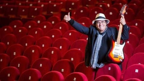 Sänger Al Bano hebt den Daumen in einem leeren Konzertraum mit roten Sitzen