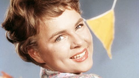 Cornelia Froboess - Kinderstar, Schauspielerin und Schlagersängerin: Die junge Sängerin Cornelia Froboess posiert auf einem Porträtfoto aus dem Jahr 1960 lächelnd mit zur Seite gedrehtem Kopf.